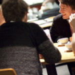 group of friends or colleagues sitting at a table in a coffee shop laughing