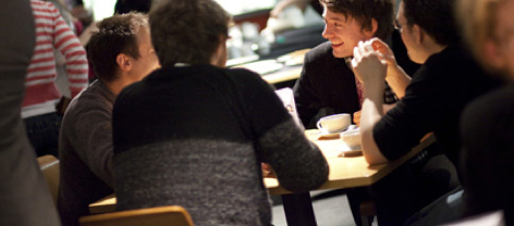 group of friends or colleagues sitting at a table in a coffee shop laughing