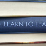 stack of textbooks with one book spine saying "Learn to Lead"