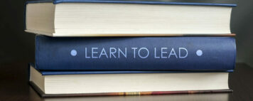 stack of textbooks with one book spine saying "Learn to Lead"