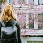 student with a backpack looking at a lush cherry tree