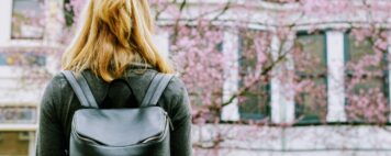 student with a backpack looking at a lush cherry tree