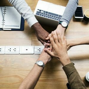 a diverse team with their hands on top of each other to suggest teamwork