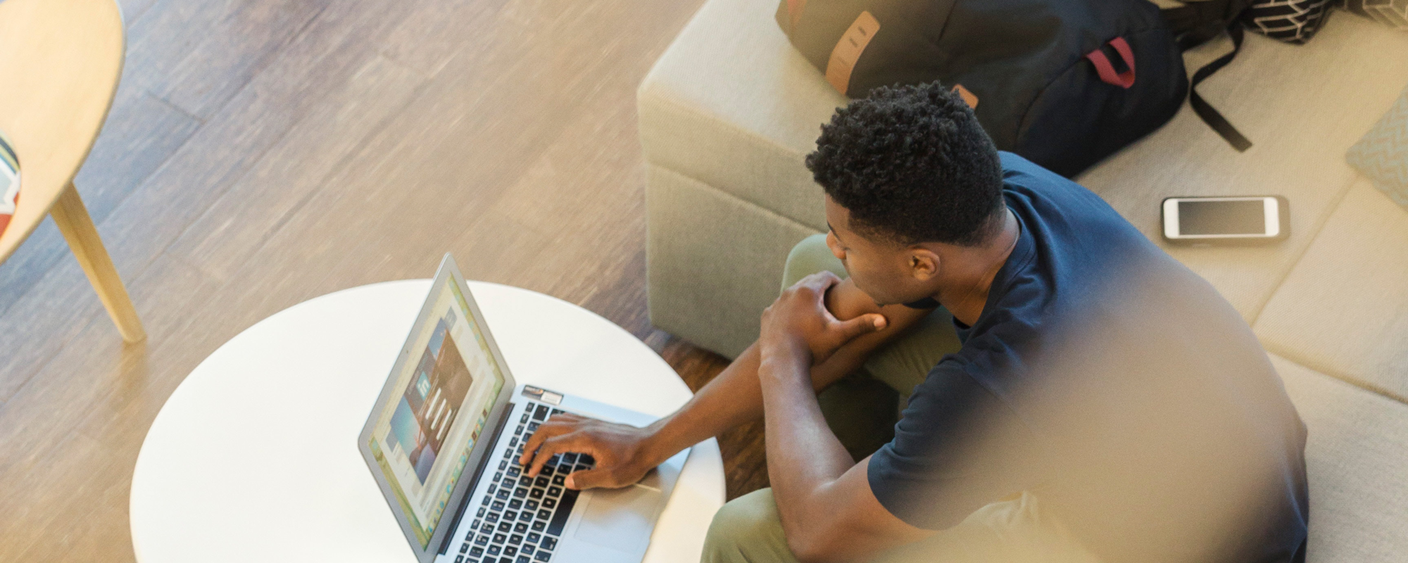 young male student using his laptop in a campus learning space.