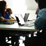 group of students with laptops open looking at a speaker/professor