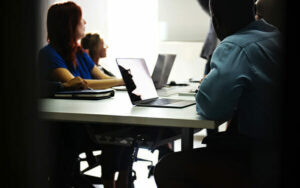 group of students with laptops open looking at a speaker/professor