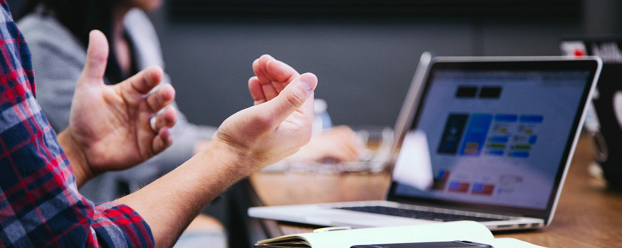 person talking with their hands to a group, all seated together at a table