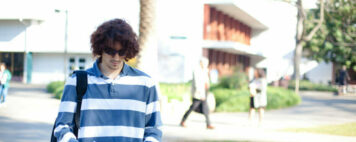 young male student walking with his head down on campus