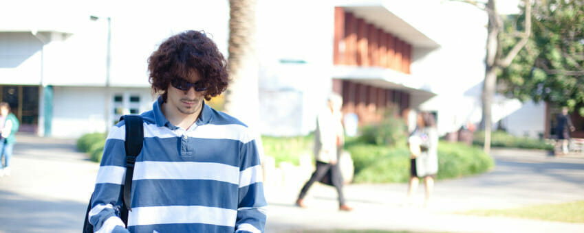 young male student walking with his head down on campus