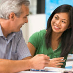 two people smiling and learning with a textbook open