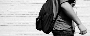 black and white image of a student walking by a brick building