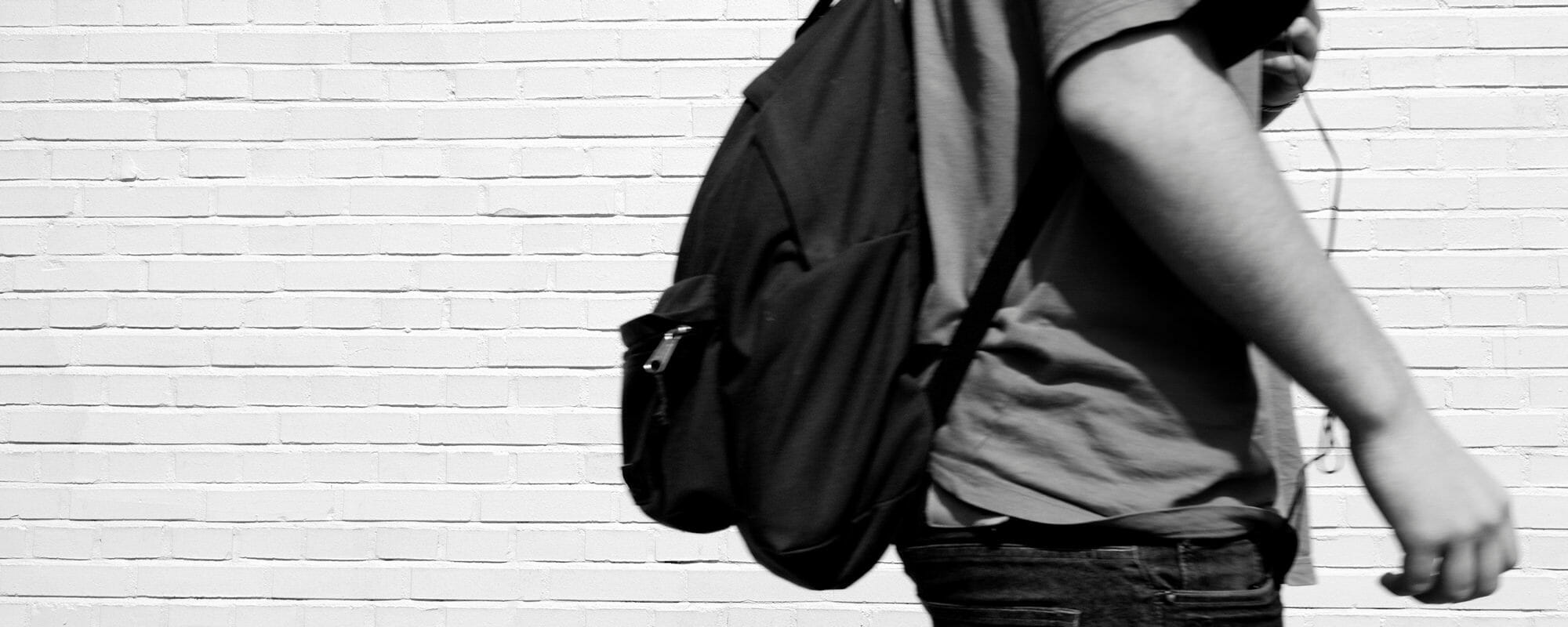 black and white image of a student walking by a brick building