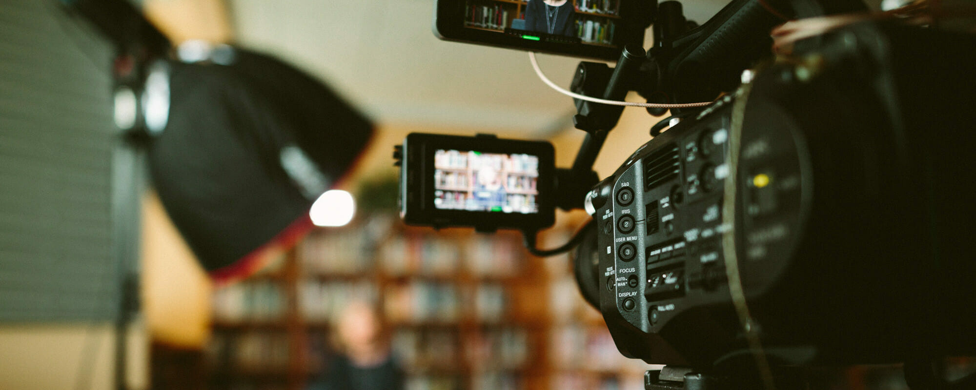 video camera with a student in front of books