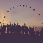 Students throwing graduation caps in an arch