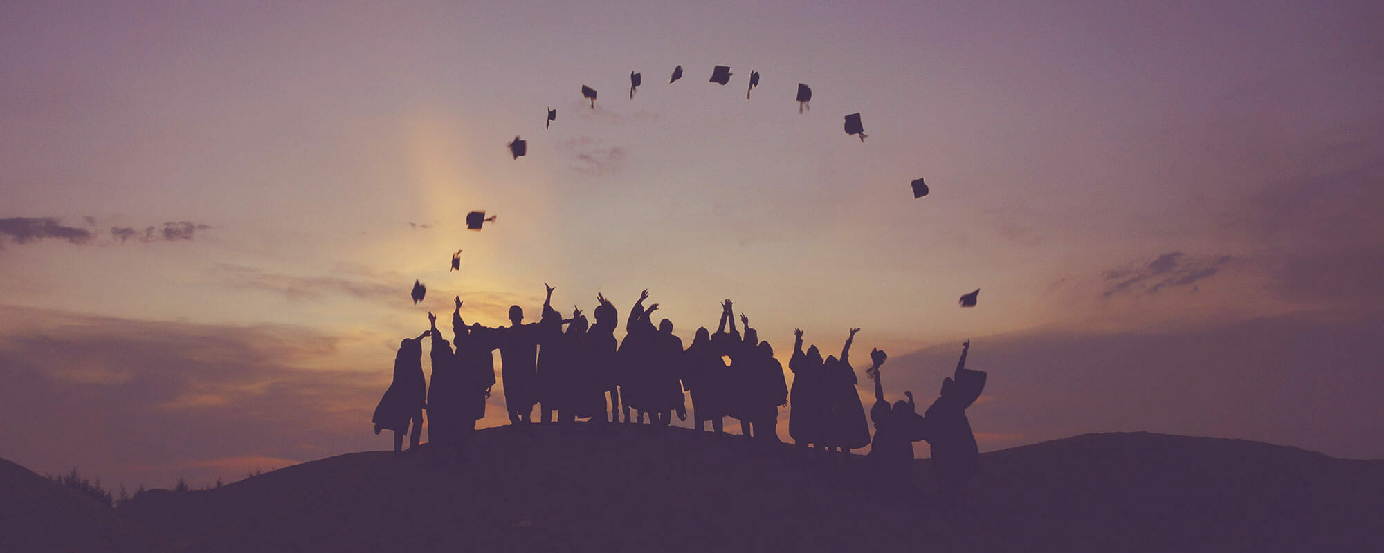 Students throwing graduation caps in an arch