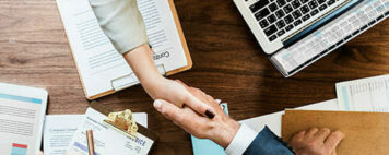 Two people shaking hands across a table.