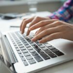 Cropped view of person's hands typing on laptop computer