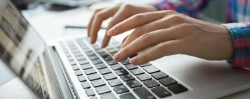 Cropped view of person's hands typing on laptop computer