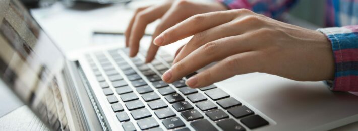 Cropped view of person's hands typing on laptop computer