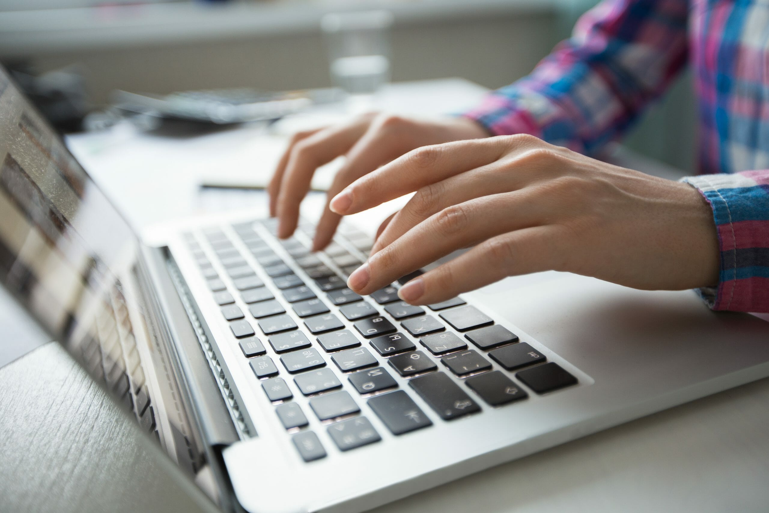 Cropped view of person's hands typing on laptop computer