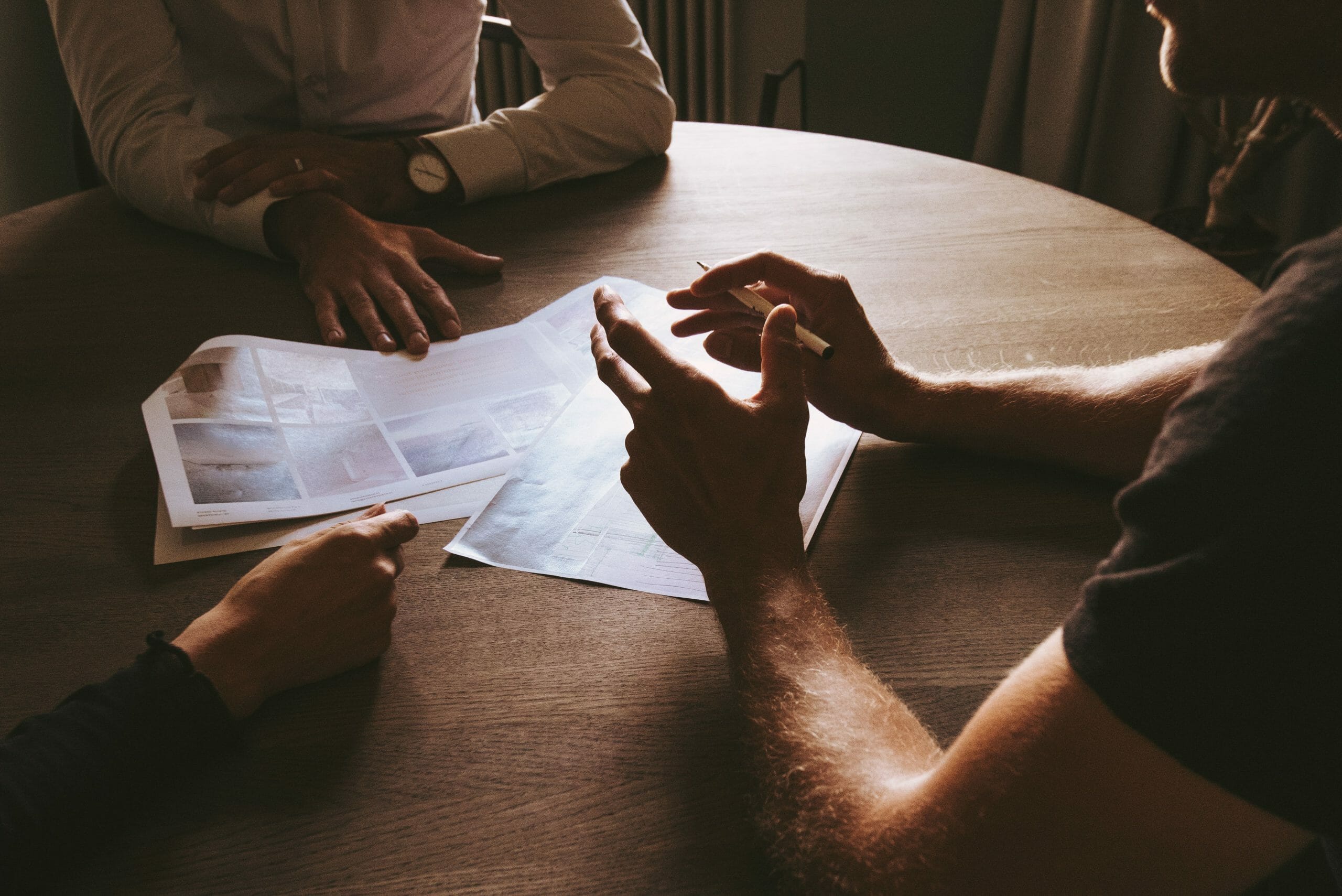 Image of several professionals having a brainstorming session at a wooden table