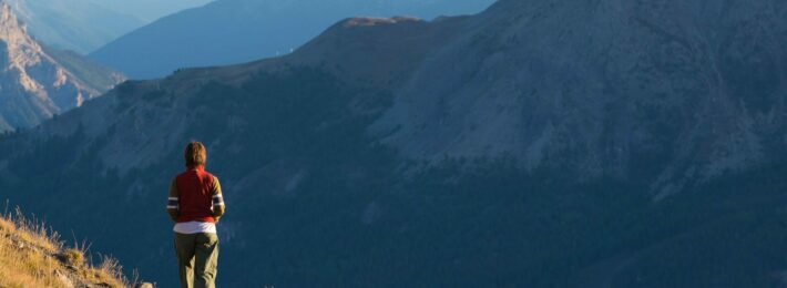 Hiker in high altitude rocky mountain landscape. Summer adventures on the Italian French Alps, toned image.