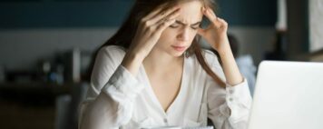 Nervous stressed woman feeling anxiety or strong headache massaging temples studying in cafe, young tired female student experiencing panic attack preparing for test or exam in public place