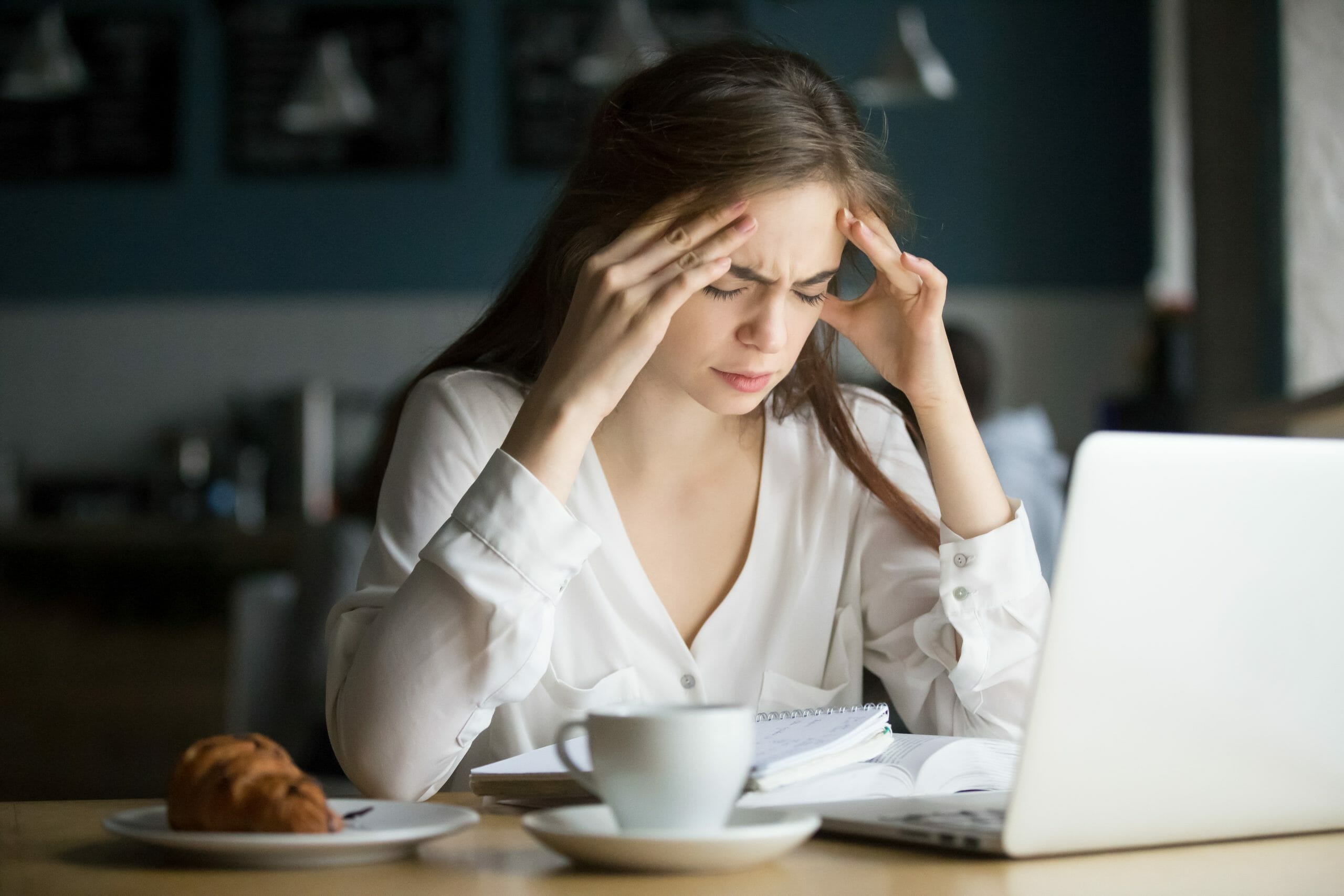 Nervous stressed woman feeling anxiety or strong headache massaging temples studying in cafe, young tired female student experiencing panic attack preparing for test or exam in public place