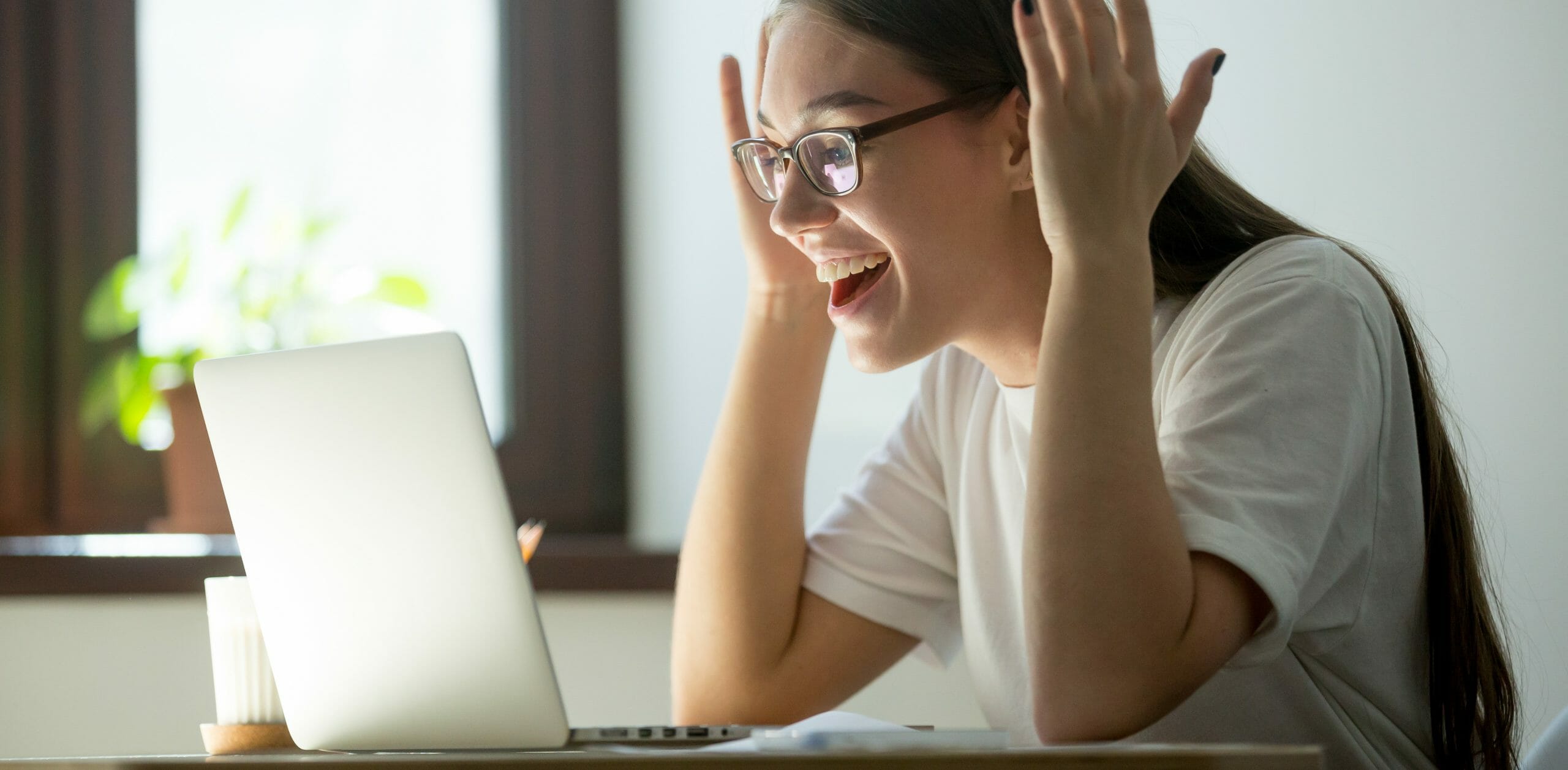 Young adult woman receiving good news via her laptop