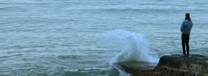 Image of a person standing alone at the edge of the sea