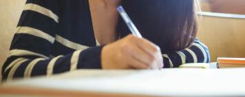 Focused student writing on notebook at the university