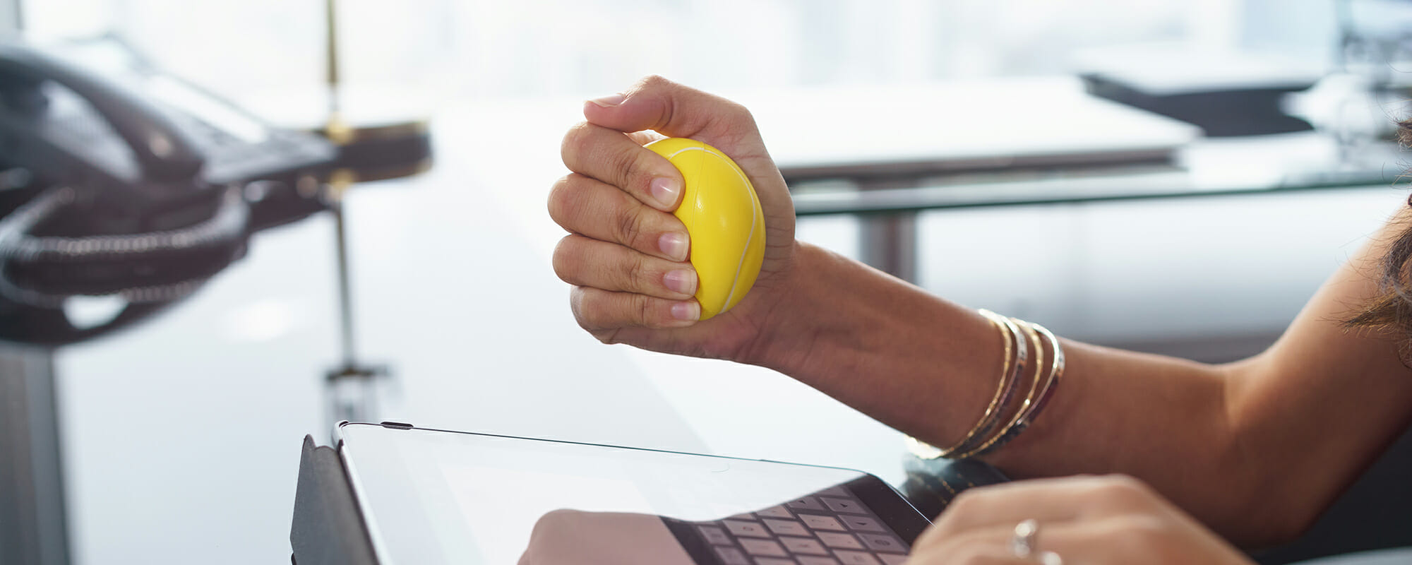 Stressed office worker with anti stress ball types email