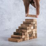 Stacking wooden blocks is at risk in creating business growth ideas.