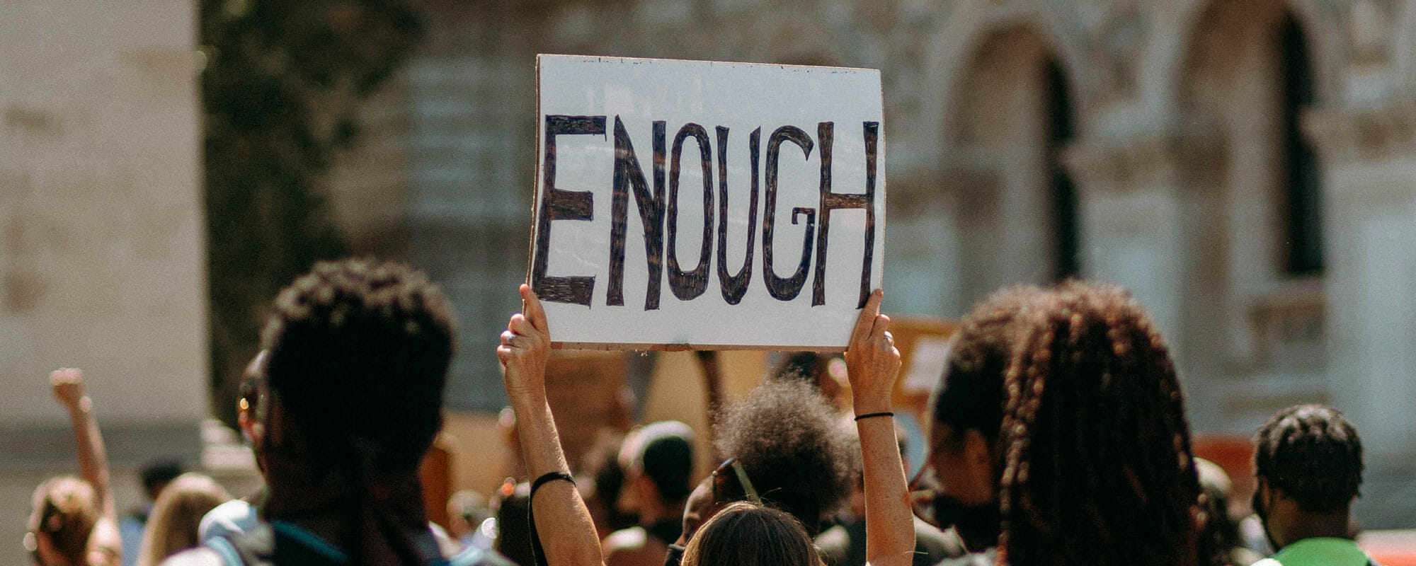 Group of protestors where one individual is holding a sign saying 