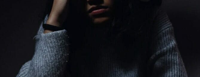 Photo of a woman seated at a desk with a cup of coffee and a distressed expression after having suffered a microaggression