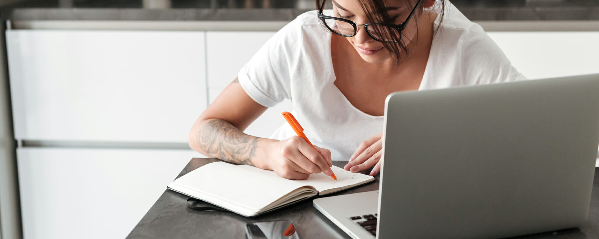 Woman taking notes while on laptop