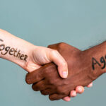 Handshake between black and white people standing together against hate