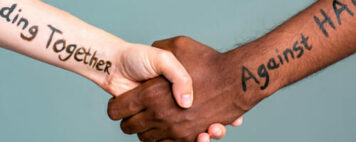 Handshake between black and white people standing together against hate