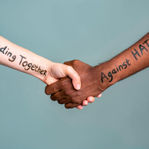 Handshake between black and white people standing together against hate