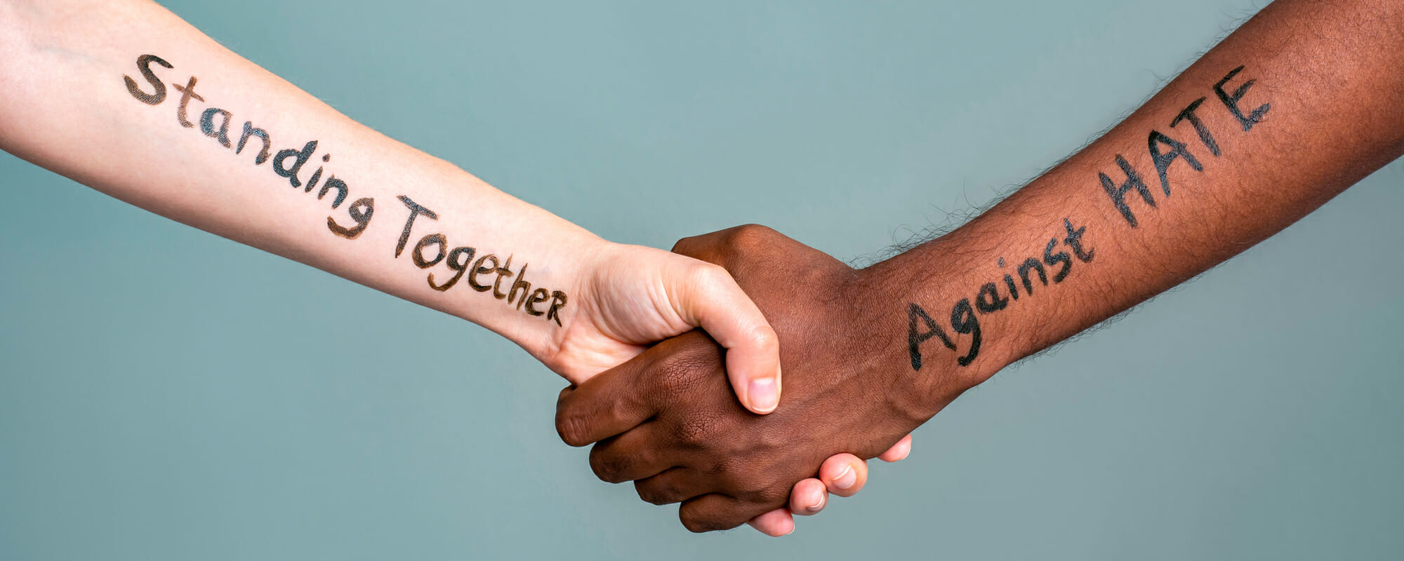 Handshake between black and white people standing together against hate