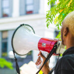 Person of color holding a megaphone at a peaceful protest
