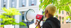Person of color holding a megaphone at a peaceful protest