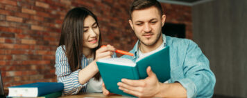 University students reading textbook together