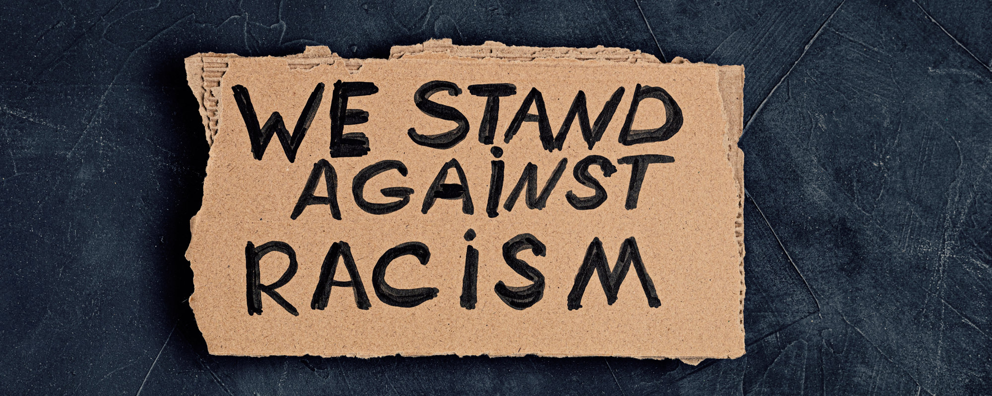 We stand against racism written on cardboard
