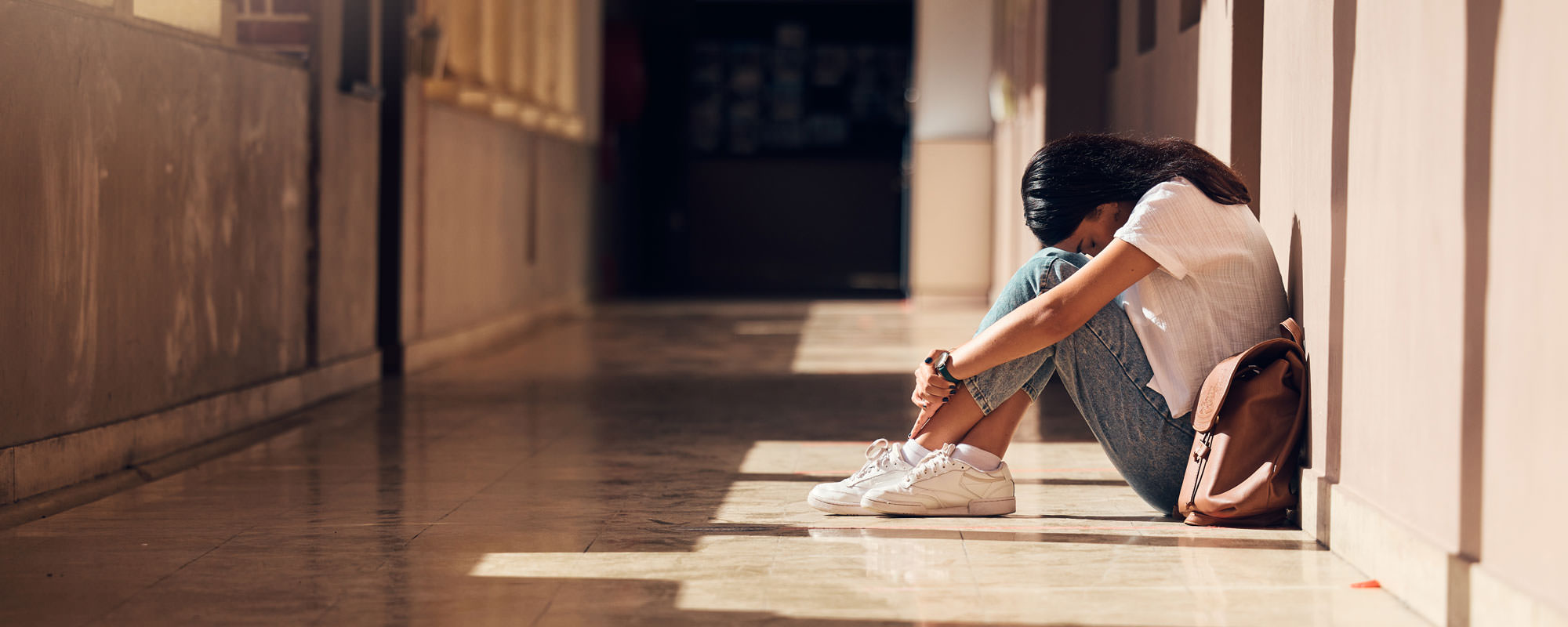 Sad young student sitting in the hall.