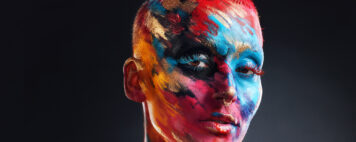 Artistic person with short hair and colorful paint on their face