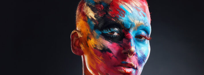 Artistic person with short hair and colorful paint on their face