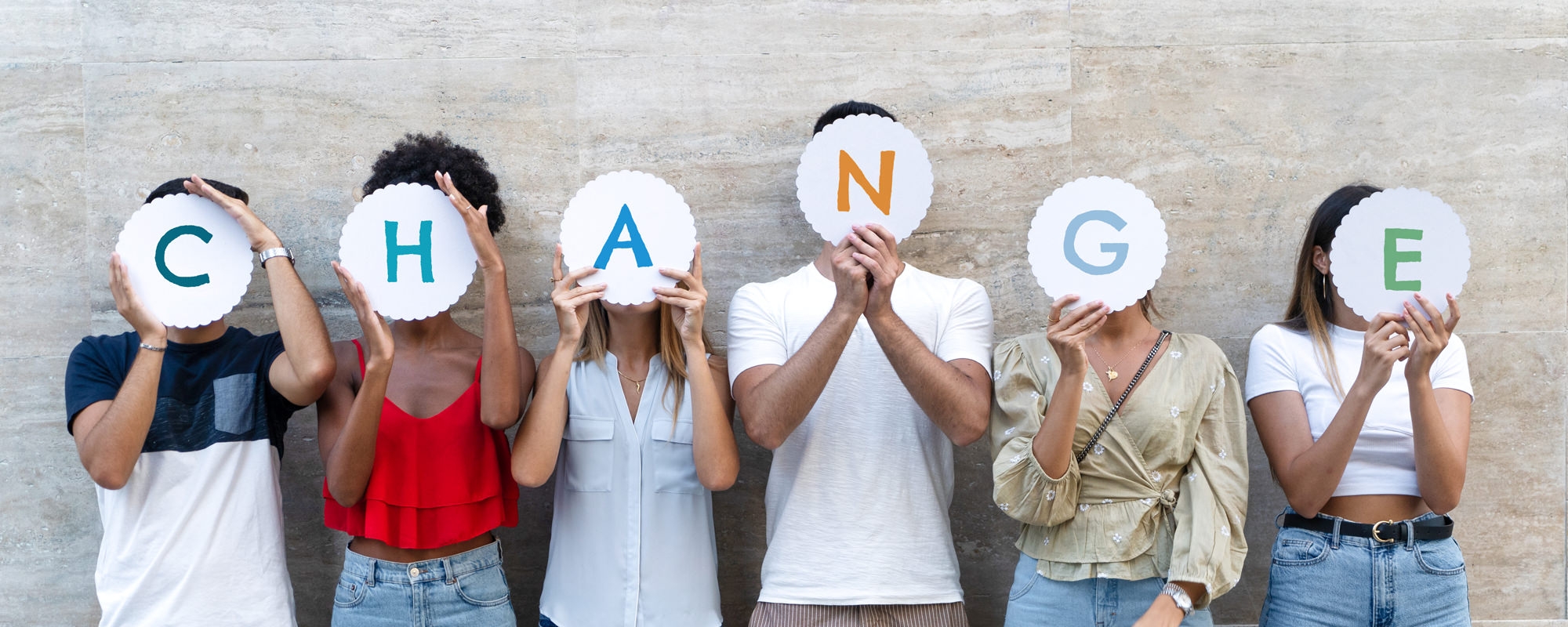 Group of people holding letter signs that spell change.